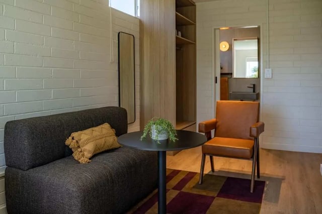 Sofa chair table plant mirror wardrobe open bathroom living room at UKO Balmain in Sydney Student Accommodation