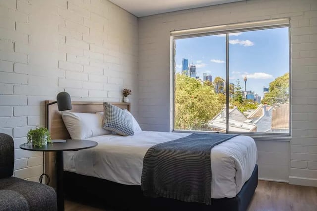 Bed bedside table lamp and city view bedroom at UKO Balmain in Sydney Student Accommodation