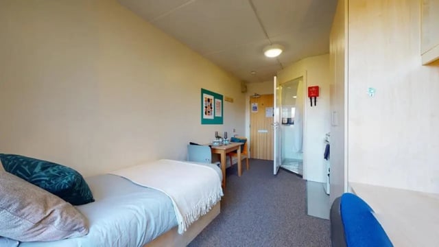 Bed table chairs shower closet bedroom at Creek Court in London Student Accommodation