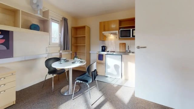 Round table two chairs microwave fridge kitchen studio at Creek Court in London Student Accommodation