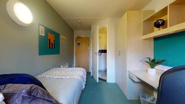 Bed desk wardrobe door and ensuite bathroom bedroom at Creek Court in London Student Accommodation