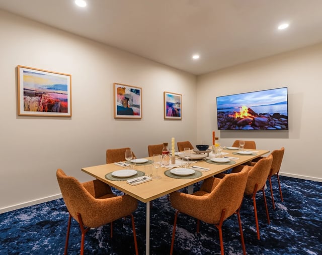 Dining table with orange chairs artwork and TV dining room at UKO Melbourne Central in Melbourne Student Accommodation
