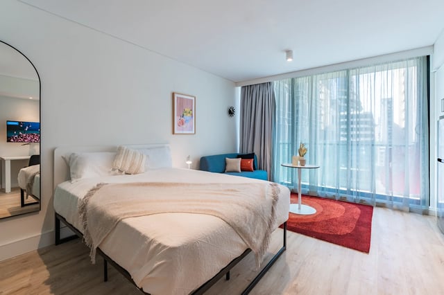 Bed sofa mirror tv and artwork bedroom at UKO Melbourne Central in Melbourne Student Accommodation