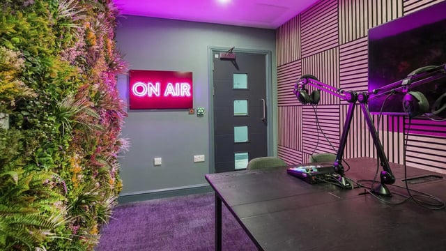 Neon sign plants desk with microphones studio room at 26 Great George Street in Leeds Student Accommodation
