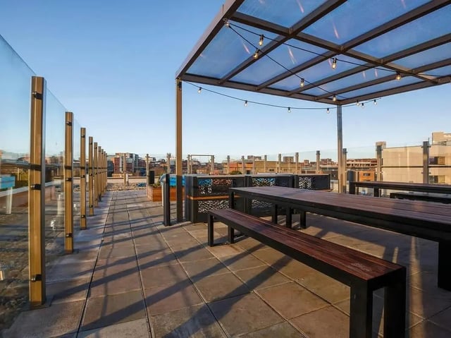 Outdoor dining tables benches glass railings patio exterior at COSMOS in Sheffield Student Accommodation