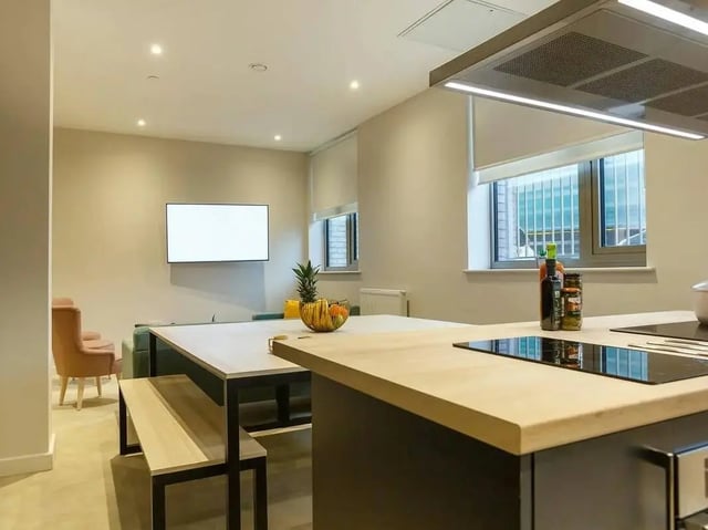 Dining table with bench and TV kitchen island living room at COSMOS in Sheffield Student Accommodation