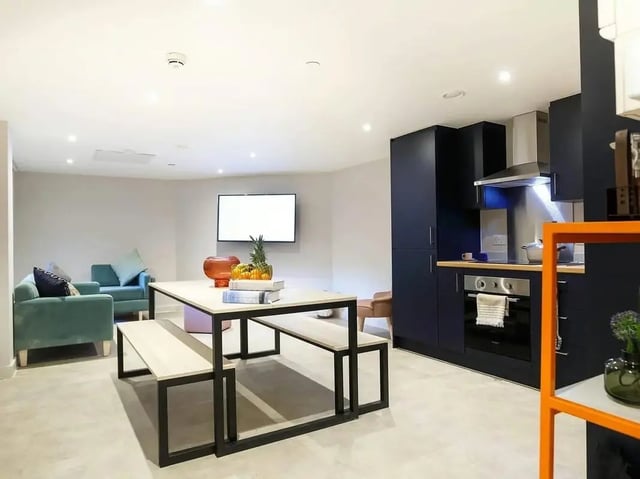 Table benches sofas television modern kitchen living area at COSMOS in Sheffield Student Accommodation