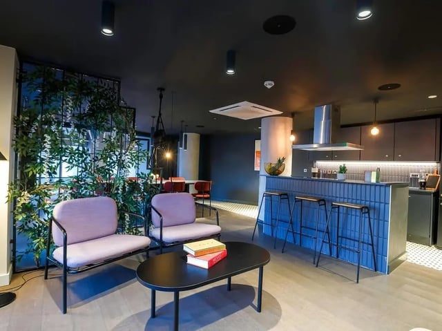 Two purple chairs black table kitchen counter stools living room at COSMOS in Sheffield Student Accommodation