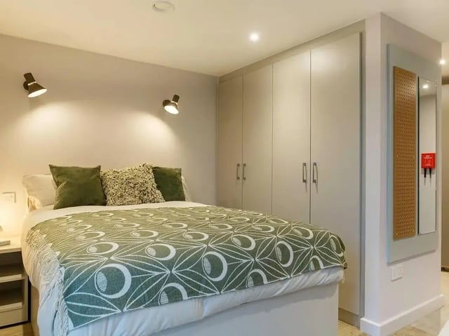 Bed with green patterned throw and wardrobe bedroom at COSMOS in Sheffield Student Accommodation