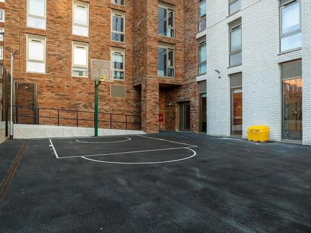 Basketball court exterior with brick buildings at COSMOS in Sheffield Student Accommodation