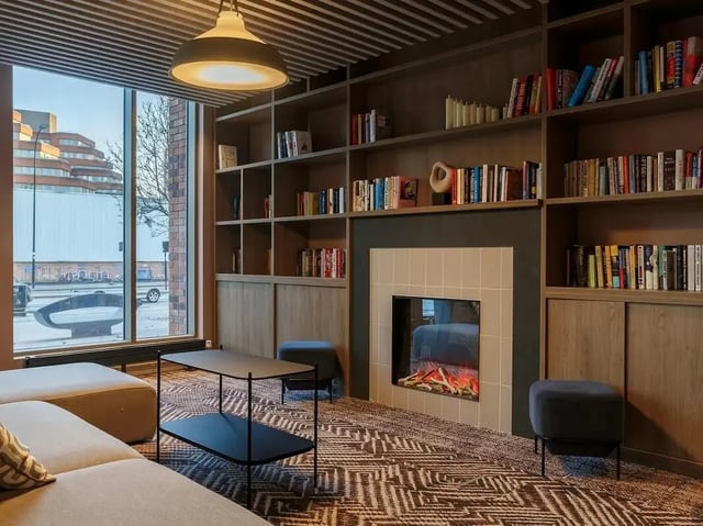 Sofa coffee table fireplace bookshelves common area at COSMOS in Sheffield Student Accommodation