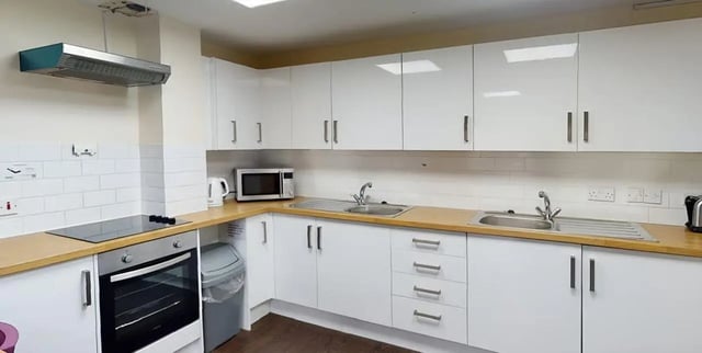 White cabinets microwave oven stovetop sink kitchen at Moulsecoomb Place in Brighton Student Accommodation