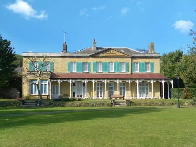 Yellow building with green shutters and porch exterior at Moulsecoomb Place in Brighton Student Accommodation