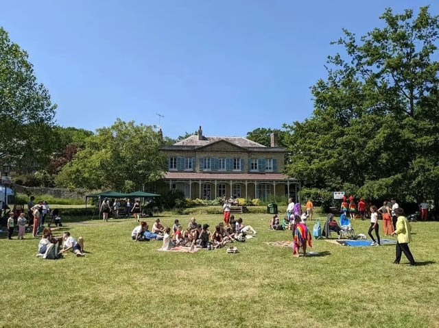 People picnicking on lawn near building exterior at Moulsecoomb Place in Brighton Student Accommodation