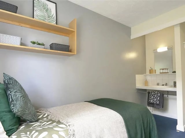 Bed with pillows and shelves above bathroom sink bedroom at Moulsecoomb Place in Brighton Student Accommodation