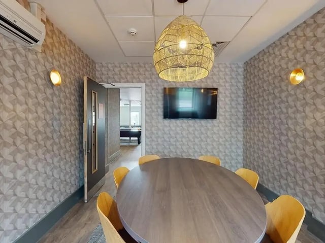 Oval table with chairs and wall mounted TV communal area at Crown Place Swansea in Swansea Student Accommodation