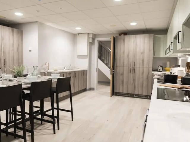 Dining table with chairs kitchen cabinets and stairs kitchen at Crown Place Swansea in Swansea Student Accommodation