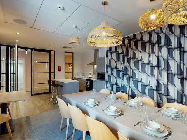 Dining table with place settings and kitchen area living room at Crown Place Swansea in Swansea Student Accommodation