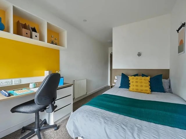Desk chair bed with yellow blue pillows bedroom at Felda House in Wembley Student Accommodation