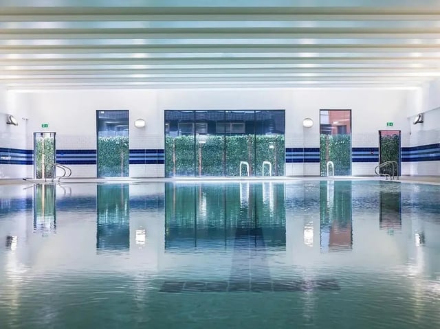 Indoor swimming pool with green wall panels and glass doors Pool at Grand Felda House in Wembley Student Accommodation