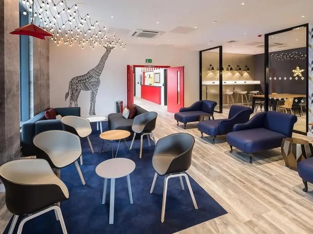 Modern lounge with sofas chairs tables and giraffe art living room at Grand Felda House in Wembley Student Accommodation
