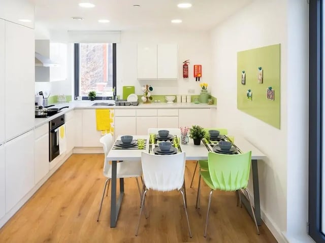 Table chairs kitchen cabinets and appliances kitchen at Grand Felda House in Wembley Student Accommodation