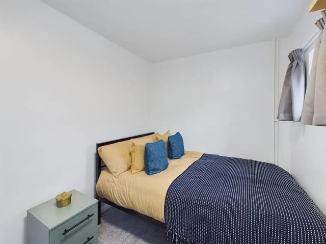 Bed with blue and gold pillows bedside cabinet Bedroom at 6 Bedroom House at 10, Mint Road in Leicester Student Accommodation