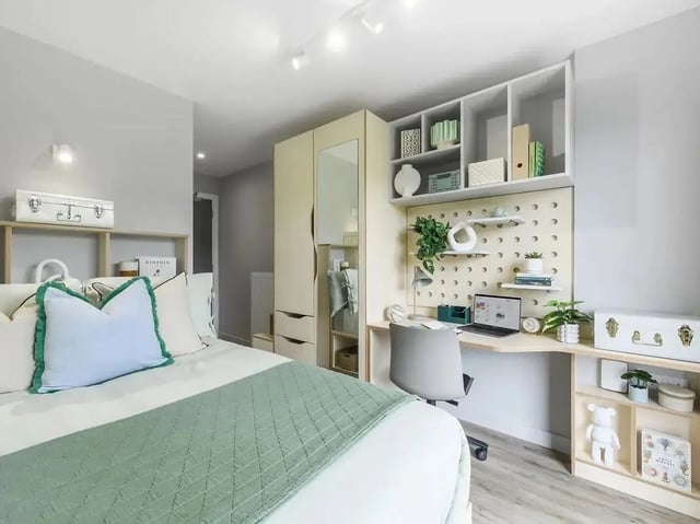 Bed with green blanket desk with laptop bedroom at Yugo Bottleworks in Cork Student Accommodation