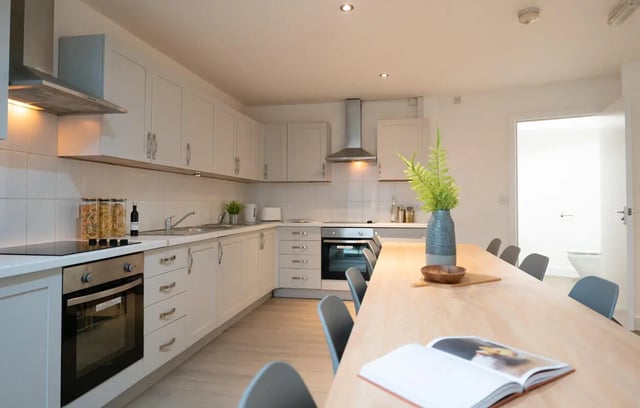 White cabinets oven hob and dining table kitchen at 12 Bedroom House at Freya House, Thesiger Street in Lincoln Student Accommodation
