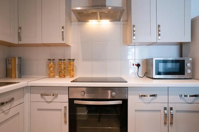 White cabinets microwave stove pasta jars books kitchen at 4 Bedroom House at 119, Oliver House, Canwick Road in Lincoln Student Accommodation