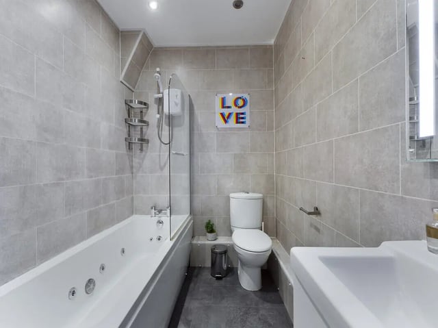 Modern bathroom with bathtub toilet sink and art. at 4 Bedroom House at 107, Hall Lane in Liverpool Student Accommodation
