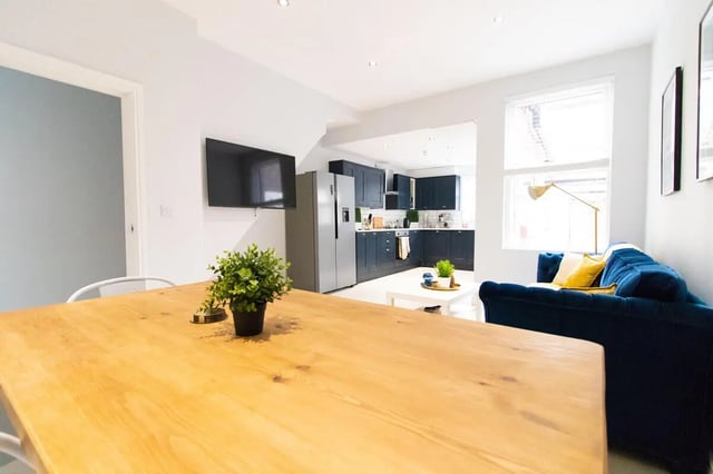 Wooden table TV dark blue kitchen couch living area at 6 Bedroom House at 85, Halsbury Road in Liverpool Student Accommodation