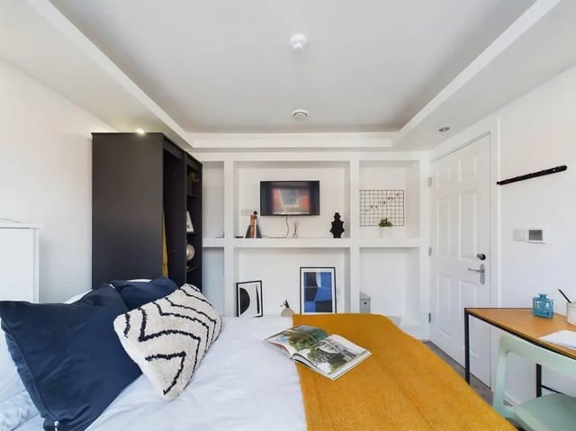 Bed with pillows yellow blanket bookshelf TV bedroom at 5 Bedroom House at 2, Crofton Street in Manchester Student Accommodation