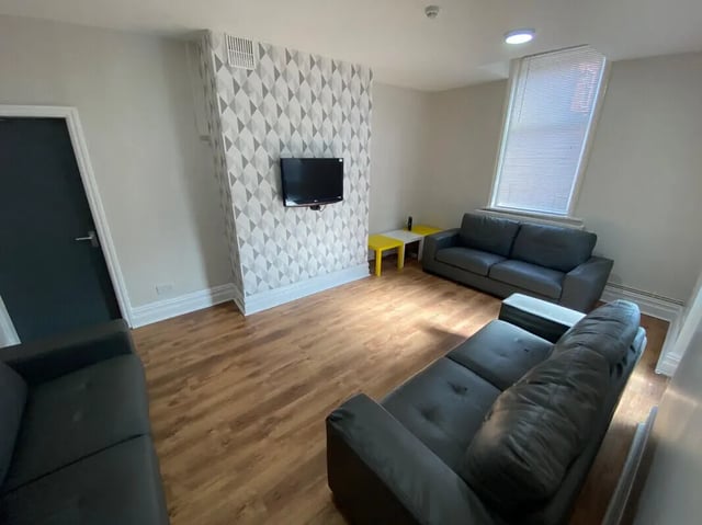 Dark sofas patterned wallpaper television yellow tables Living Room at 8 Bedroom House at 73, Dallas Street in Preston Student Accommodation