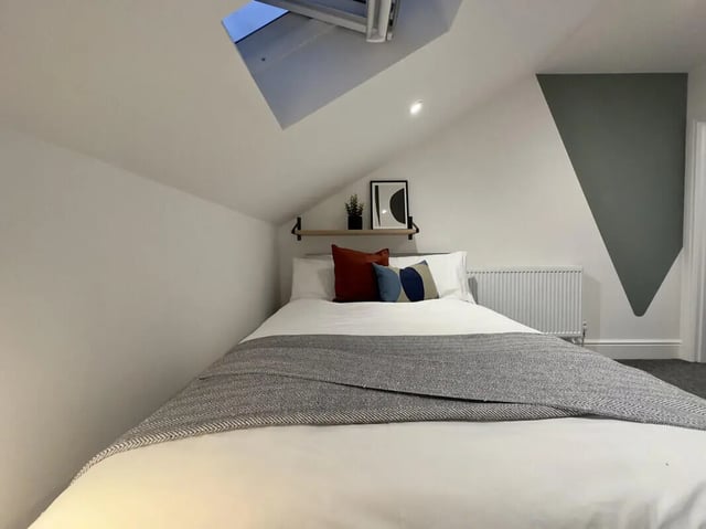 Bed with pillows artwork shelf and skylight bedroom at 6 Bedroom House at 45, Monks Road in Lincoln Student Accommodation