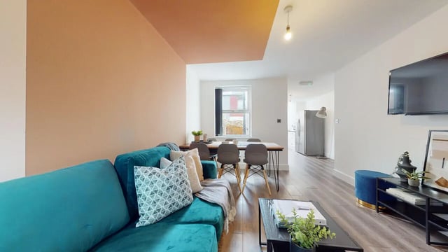 Turquoise sofa dining table grey chairs living room at 6 Bedroom House at 18, Halsbury Road in Liverpool Student Accommodation