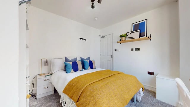 Bed with yellow throw blue pillows bedside table bedroom at 6 Bedroom House at 18, Halsbury Road in Liverpool Student Accommodation