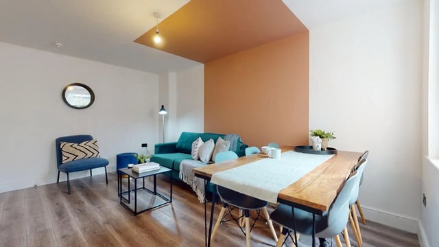 Green sofa and wooden dining table living room at 6 Bedroom House at 18, Halsbury Road in Liverpool Student Accommodation