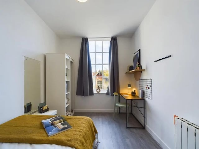 Bed with yellow throw desk with lamp bookshelf bedroom at 5 Bedroom House at Flat 4, 18, China Street in Lancaster Student Accommodation