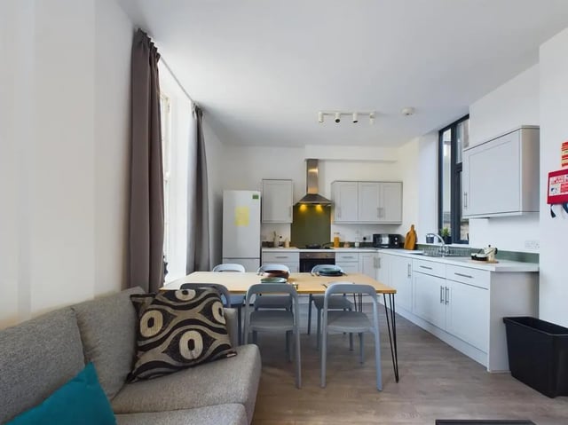 Sofa dining table chairs kitchen cabinets refrigerator kitchen area at 5 Bedroom House at Flat 4, 18, China Street in Lancaster Student Accommodation
