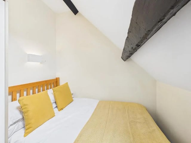 Wooden bed with yellow pillows bedroom at 4 Bedroom House at Flat 9, 18, China Street in Lancaster Student Accommodation