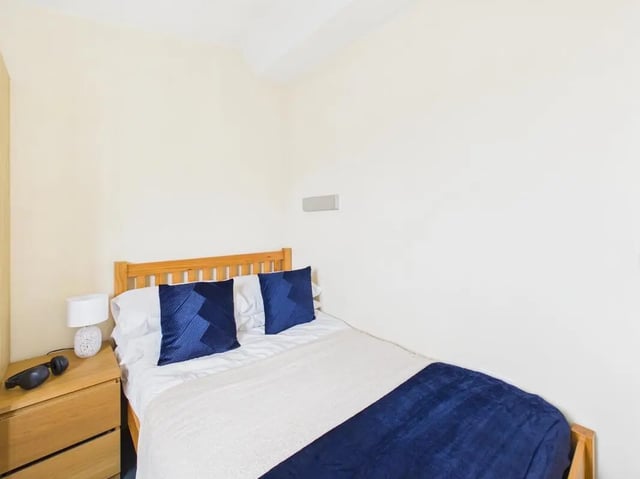 Wooden bed with blue cushions bedside table lamp bedroom at 4 Bedroom House at Flat 9, 18, China Street in Lancaster Student Accommodation