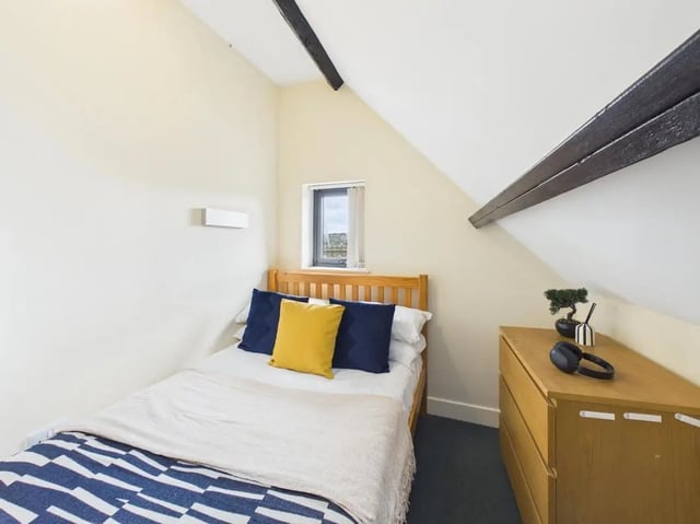Bed with blue and yellow pillows dresser with headphones bedroom at 4 Bedroom House at Flat 9, 18, China Street in Lancaster Student Accommodation