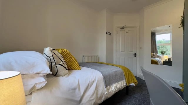 Bed with yellow pillows and grey throw bedroom at 6 Bedroom House at 214, West Parade in Lincoln Student Accommodation