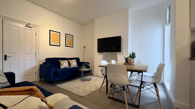Blue sofa rug table and chairs living room at 6 Bedroom House at 214, West Parade in Lincoln Student Accommodation
