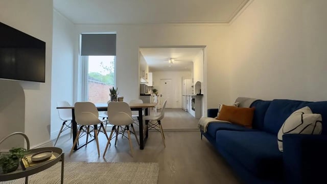 Dining table chairs blue couch and kitchen living room at 6 Bedroom House at 214, West Parade in Lincoln Student Accommodation
