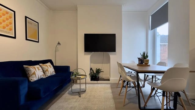 Blue sofa, dining table, and chairs living room at 6 Bedroom House at 214, West Parade in Lincoln Student Accommodation