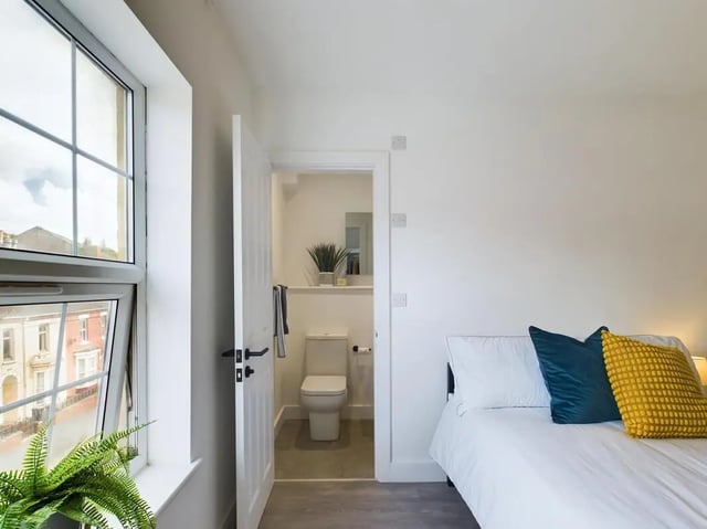 Bed with pillows and open door to bathroom at 8 Bedroom House at 69, Monks Road in Lincoln Student Accommodation