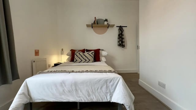Bed with pillows radiator shelf and coat bedroom at 3 Bedroom House at 25, Romney Street in Salford Student Accommodation