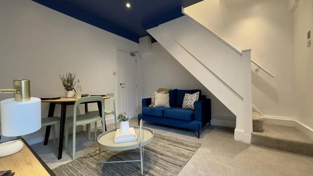 Blue sofa dining table and stairs living room at 3 Bedroom House at 25, Romney Street in Salford Student Accommodation